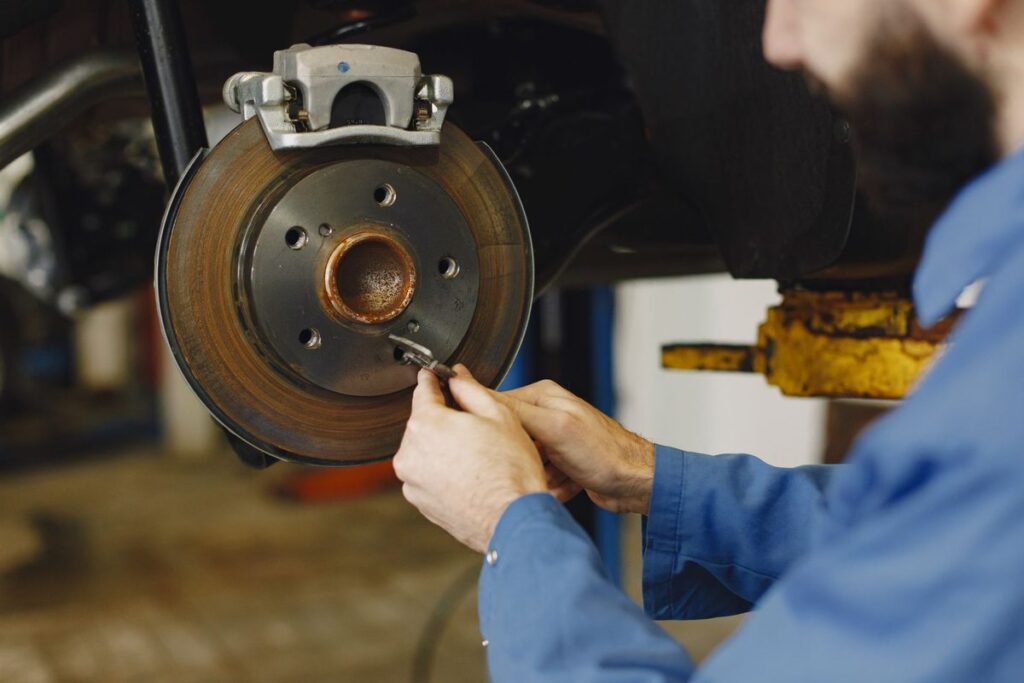 Mechanic inspecting brake disc and caliper during brake repair service in Dubai at Shabab Al Lisaili Auto Electric Repair
